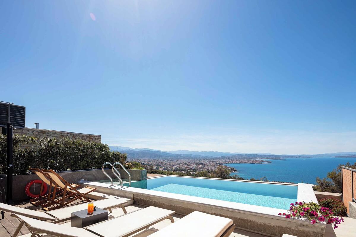 Piscina no terraço com espreguiçadeiras e vista para o mar.