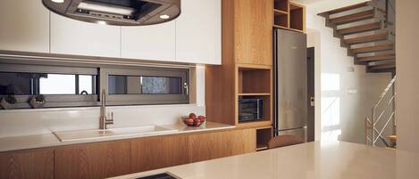 A modern kitchen with a built-in microwave, a stainless steel range hood, and wooden cabinetry.
