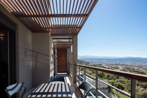 A balcony with a wooden pergola, a table, two chairs, and a view of a city and mountains in the distance. - Omnia Villas - Holiways Collection (Chania)