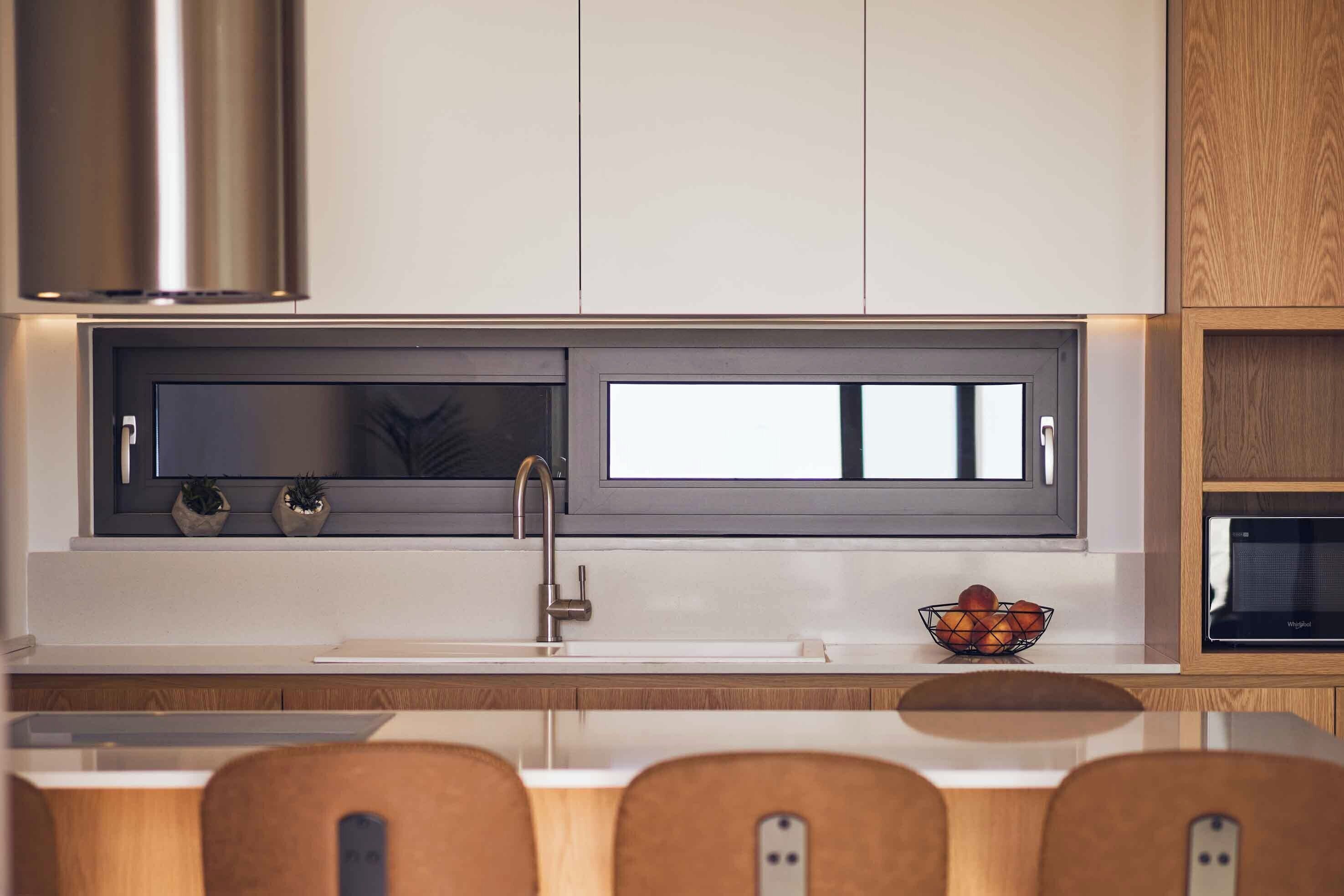 A modern kitchen with a built-in window, stainless steel appliances, and wooden cabinetry.