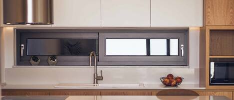 A modern kitchen with a built-in window, stainless steel appliances, and wooden cabinetry.