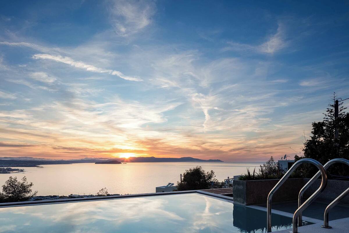 Piscina com vista para o pôr do sol sobre a água.