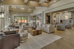 A spacious living room with a fireplace, a pool table, and a large window.