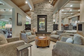 A spacious living area with a stone fireplace, comfortable seating, and a view of the outdoors.