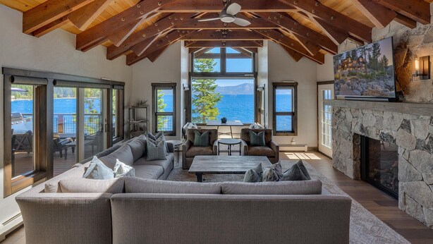 A spacious living room with a large sofa, a fireplace, and a view of the sea.