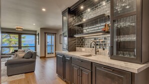 A modern kitchen with dark cabinetry, a marble countertop, and a built-in wine rack.