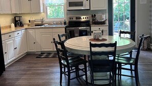 A kitchen with white cabinets, a round dining table, and a black countertop. - Quiet, clean, jacuzzi hot tub. hidden gem, families. Skyline Park & Massanutten. (Elkton)