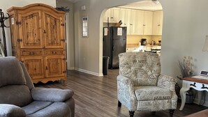 A spacious living room with a dark wood floor, a grey recliner, a patterned armchair, and a wooden coffee table. A ceiling fan is visible above. - Quiet, clean, jacuzzi hot tub. hidden gem, families. Skyline Park & Massanutten. (Elkton)