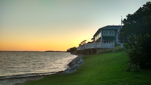 A coastal house with a grassy lawn and a view of the ocean.