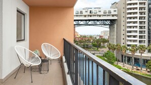 A balcony with two white chairs and a small table, overlooking a river and a bridge. - Water Edge 502 (Cape Town)