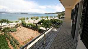 Ein Balkon mit Meerblick, ein Gartenbereich und ein Fliesenboden.