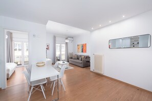 Ein modernes Wohnzimmer mit einem weißen Sofa, einem Esstisch mit Stühlen und einem großen Spiegel an der Wand.