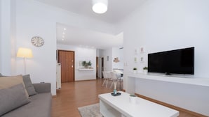 Un salon moderne avec un canapé gris, une table basse blanche et un téléviseur à écran plat fixé au mur.
