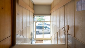 Un couloir aux murs lambrés et une porte vitrée donnant sur un espace de stationnement.