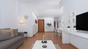 Un salon moderne avec un canapé gris, une table basse blanche et un téléviseur à écran plat.