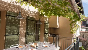 An outdoor dining area with a table set for two, featuring a polka dot tablecloth and a bottle of wine. - Maison de Vacances Avec Piscine Privée Dans le Centre de Saint Rémy de Provence (Saint-Rémy-de-Provence)