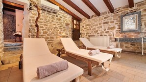 A stone-walled room with two sun loungers, a wooden bench, and a radiator. - Rustic Villa Katarina Gračišće with pools and a sauna (Gracisce)