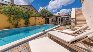 A swimming pool with lounge chairs, a stone wall, and a staircase leading to a covered area. - Rustic Villa Katarina Gračišće with pools and a sauna (Gracisce)