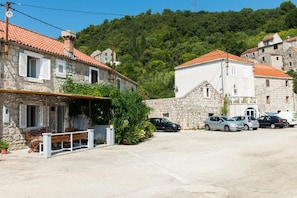 A stone building with a red-tiled roof, a bench outside, and several parked cars. - Holiday Home Anima Maris (Ston)
