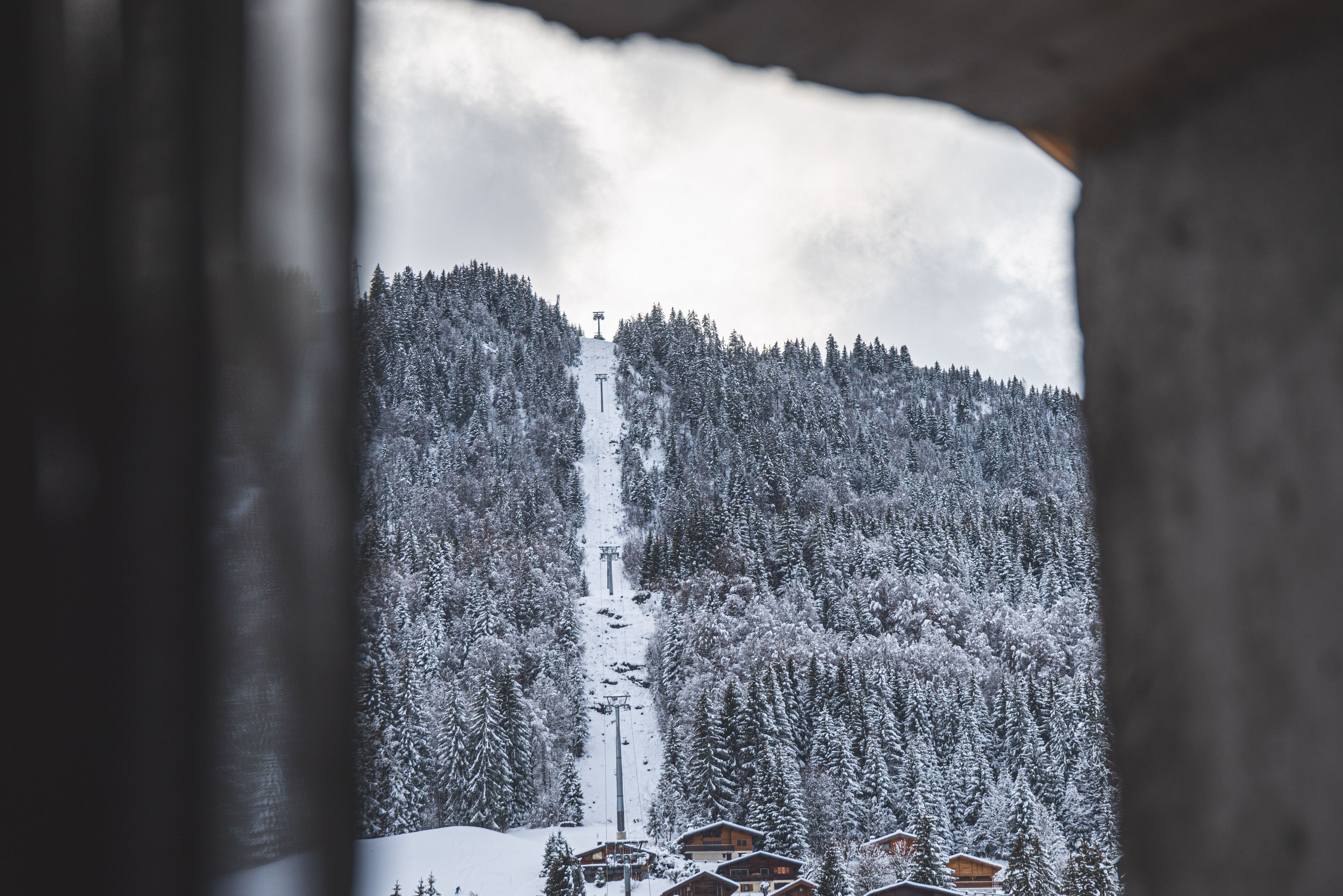 A snowy mountain landscape with a ski lift and cabins.