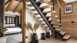 Un interior moderno con una escalera de madera, una cama y un cuadro colgado en la pared.