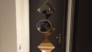 Eine dunkelbraune Tür mit diamantförmigen Spiegeln und einem runden Spiegel, der eine Person reflektiert.