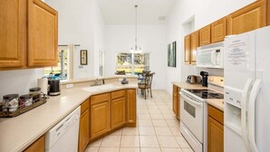 A kitchen with wooden cabinets, a white countertop, a built-in oven, a microwave, and a dishwasher. - 418 - Fabulous 4 Bed Home with South Facing Pool and Spa (Davenport)