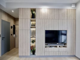 Una sala de estar moderna con televisor empotrado, paneles de madera y estantes con adornos.