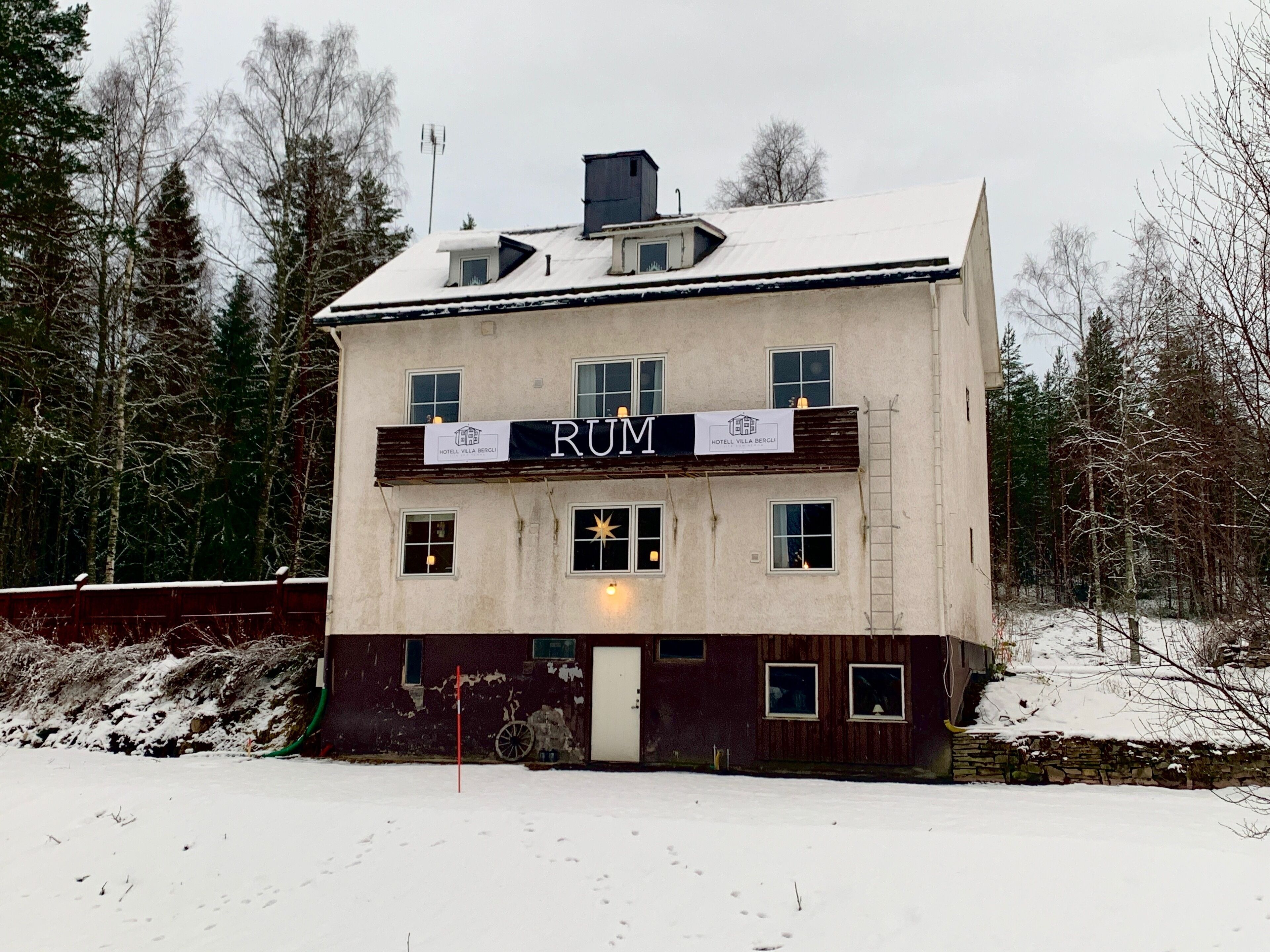 En tvåvåningsbyggnad med en skylt som visar orden "RUM" och "HOTEL VILLA BERGI".