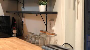 A kitchen with a toaster, a shelf with wine glasses, and a potted plant.