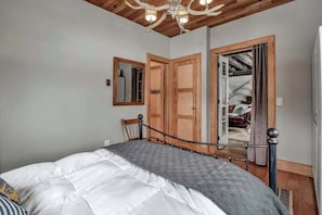 Ein Schlafzimmer mit einem Bett, Holztüren, einem Spiegel und einer Kandelaber.