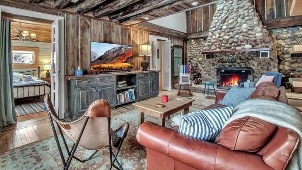 A cozy living room with a stone fireplace, leather furniture, and a television. - Rustic Cabin, Wood Fireplace & Large Deck (Great Valley)