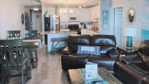 Una sala de estar moderna con un sofá de cuero, comedor y cocina.