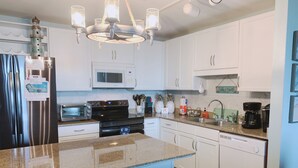 Una cocina moderna con armarios blancos, electrodomésticos de acero inoxidable, encimera de granito y una isla central con banco.