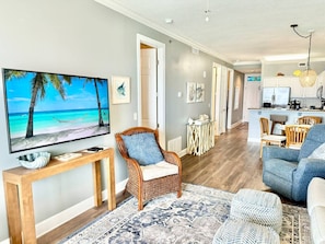 Relax in this stylish living room with a flat-screen TV, wicker armchair, and comfortable sofa.