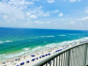 A beach with people, umbrellas, and a railing.