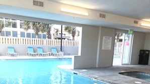 A swimming pool with a clear blue water, a poolside area with lounge chairs, and a view of a building with a white fence and palm trees. - Premiere Complex. Beachfront Penthouse Unit W/ Amazing View, Extra Large Balcony (Gulf Shores)