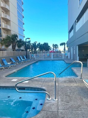 Relax by the pool surrounded by lounge chairs and palm trees.