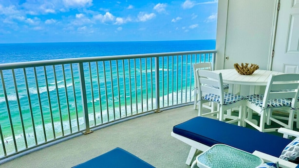 A balcony with a view of the ocean, a table with chairs, and lounge chairs. - Premiere Complex. Beachfront Penthouse Unit W/ Amazing View, Extra Large Balcony (Gulf Shores)