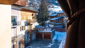 A traditional wooden building with balconies and a snow-covered courtyard. - Chalet Marcel et Grégoire (Les Belleville)