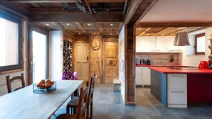 A modern kitchen with a red countertop, wooden cabinets, and a built-in island. - Chalet Marcel et Grégoire (Les Belleville)