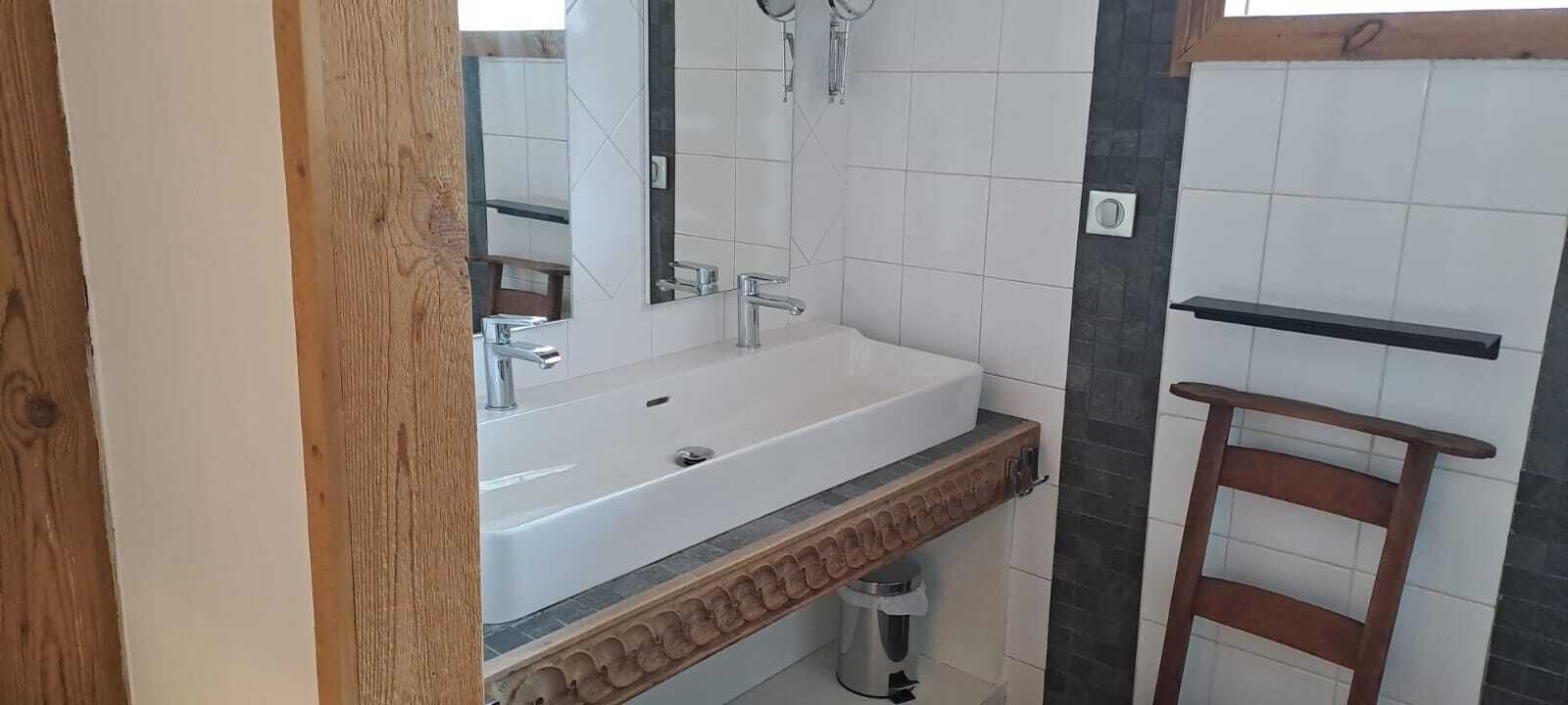 A bathroom with a white sink, a mirror, and a shower area.