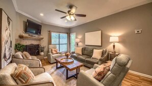 A living room with a ceiling fan, a television, a fireplace, and a sofa.