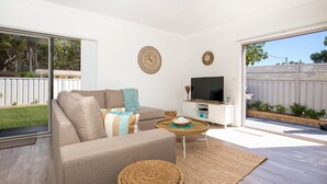 Ein modernes Wohnzimmer mit einer Couch, einem Fernseher und einem Essbereich mit Tisch und Stühlen.