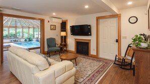 A living room with a sofa, armchair, TV, fireplace, and a view of a pool through a glass door. - The Green Room unit 4-Private Suite, Starry Skies -20 mins to Wells & Ogunquit (North Berwick)