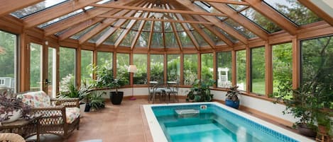 Un invernadero con piscina, vigas de madera y plantas en macetas.