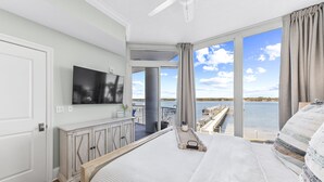 Une chambre avec un grand lit, une télévision et une vue sur un quai et l’eau.
