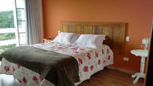 A bedroom with a wooden headboard, a floral bedspread, and a bedside table with a lamp.