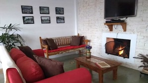 A living room with a red sofa, a wooden bench, a coffee table, and a fireplace.