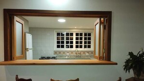 A kitchen with a window, a sink, and three bar stools.